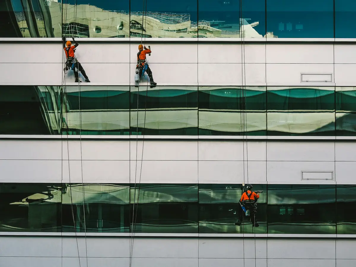 Fensterreiniger an der hellen Glasfassade eines Gewerbegebäudes