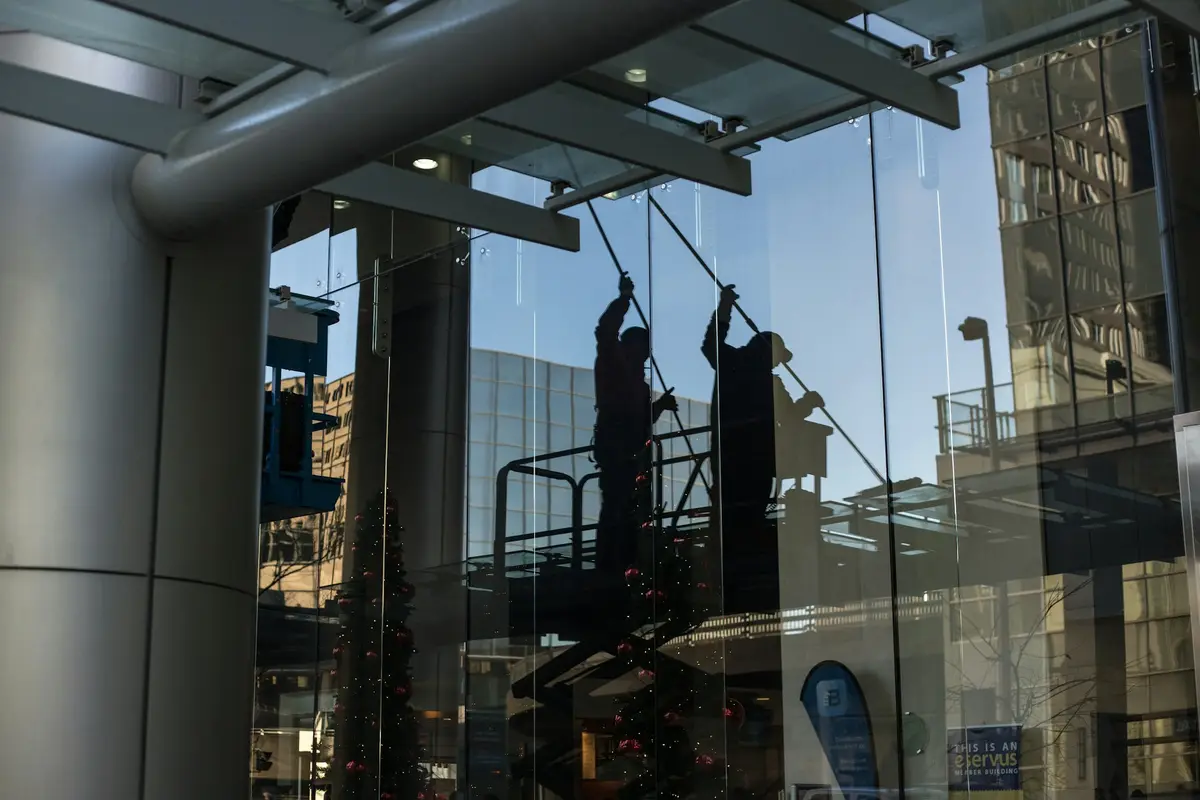 Glasreiniger auf einer Hebebühne reinigt die Glasfassade eines modernen Gebäudes