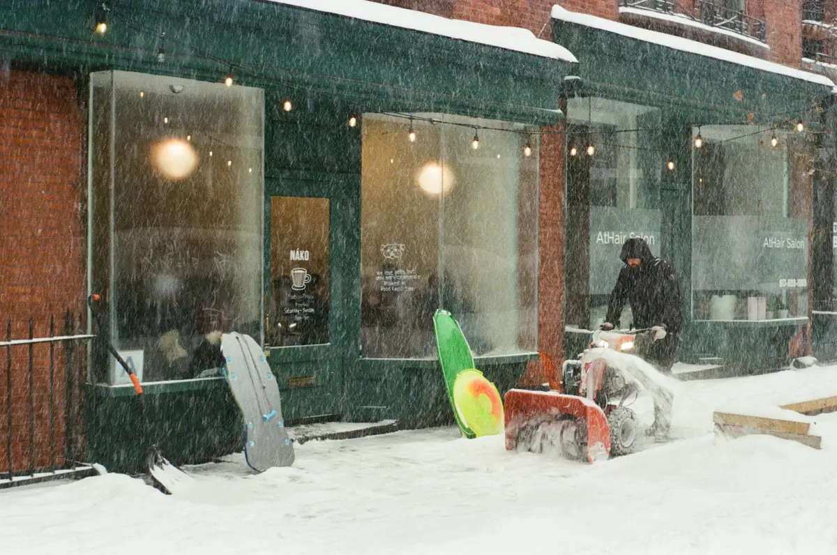 Gehweg vor einem Geschäft wird im Winter von Schnee geräumt